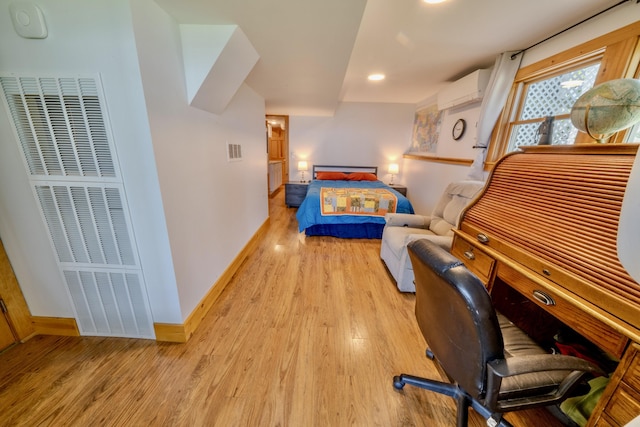 bedroom featuring a wall unit AC and light wood-type flooring