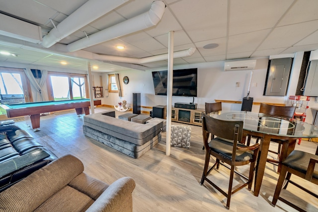 recreation room with billiards, a wall mounted AC, a drop ceiling, electric panel, and light hardwood / wood-style floors