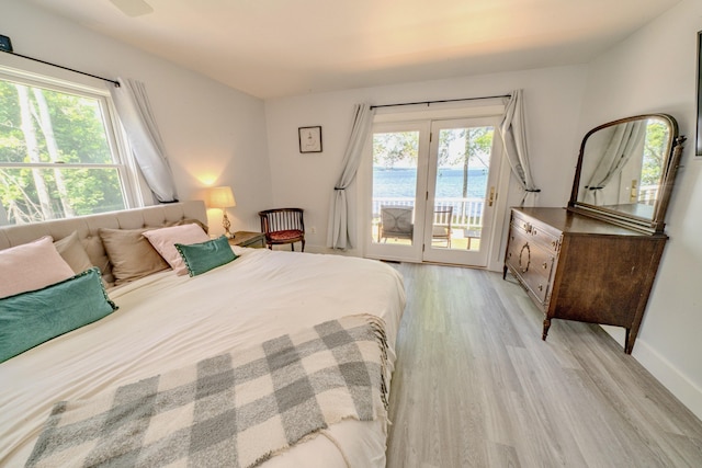 bedroom featuring access to outside, a water view, and light hardwood / wood-style flooring