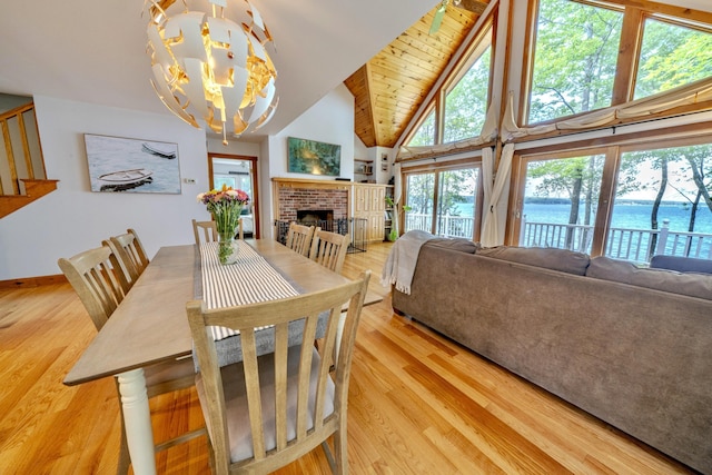 dining area featuring a brick fireplace, hardwood / wood-style floors, a notable chandelier, and a water view