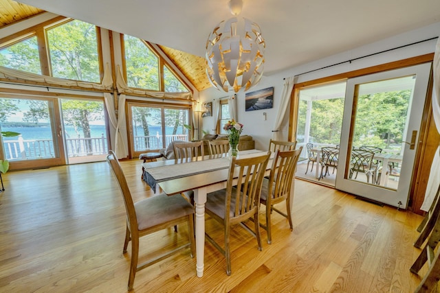 dining area with wooden ceiling, a wealth of natural light, a notable chandelier, and a water view