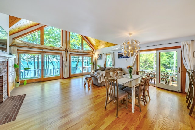 dining room featuring wood ceiling, a notable chandelier, a fireplace, vaulted ceiling, and light hardwood / wood-style flooring