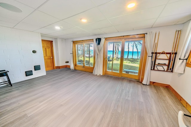 unfurnished living room featuring a drop ceiling and light hardwood / wood-style flooring