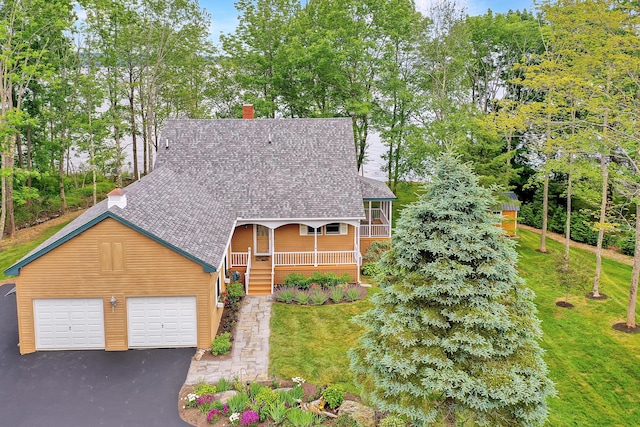 view of front of house featuring covered porch, a front lawn, and a garage