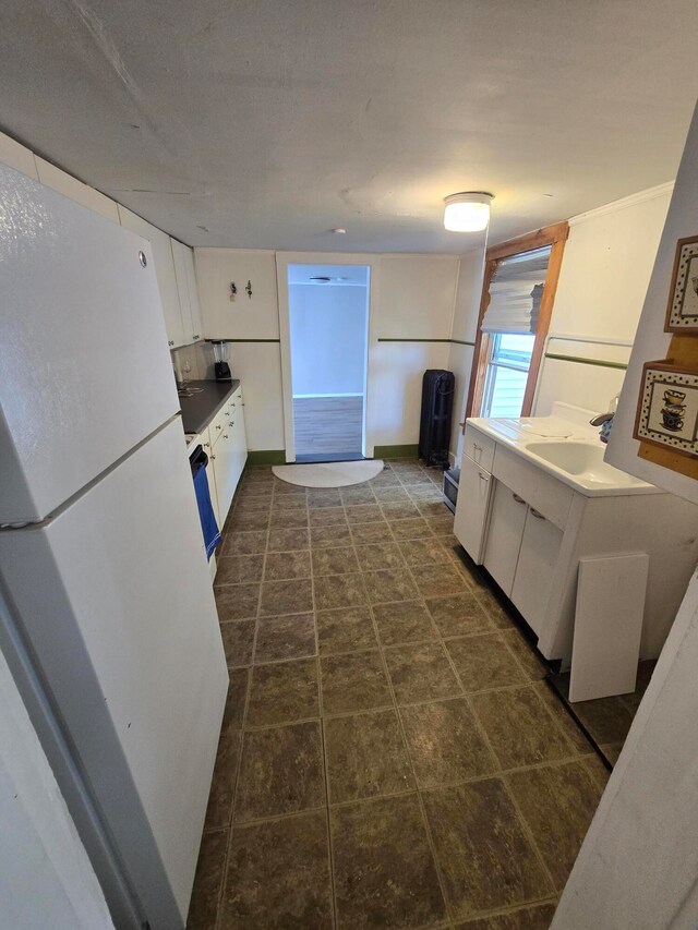 kitchen with white cabinets, white fridge, and sink