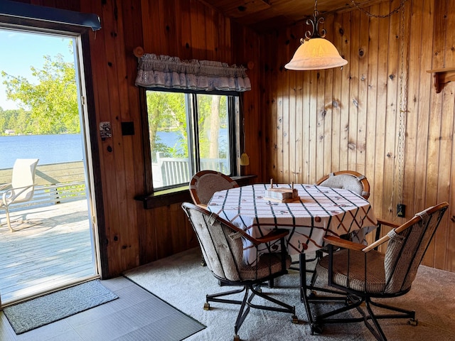 dining area with a wealth of natural light, carpet, and wood walls