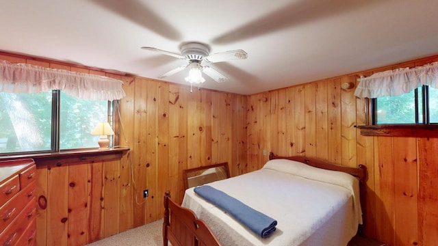 bedroom featuring ceiling fan, carpet, and wood walls