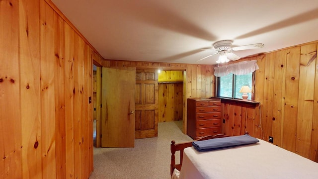 bedroom with ceiling fan, light carpet, and wooden walls