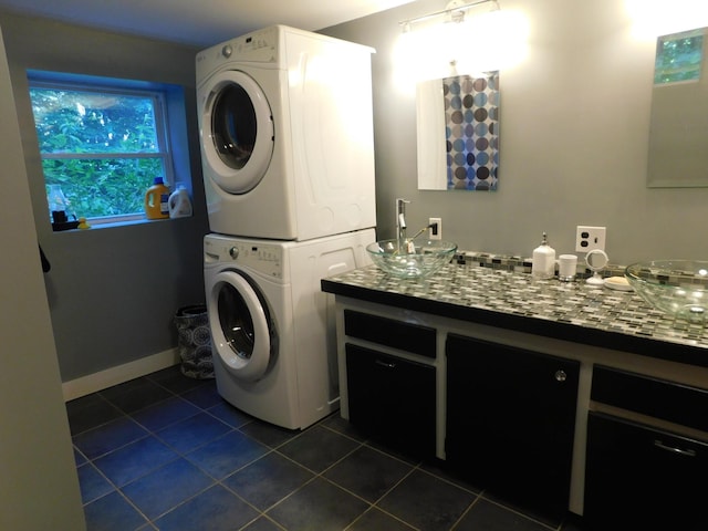 laundry room featuring stacked washer and dryer, sink, and dark tile patterned floors