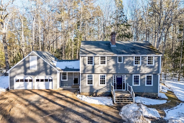 colonial house with a garage, driveway, and a chimney