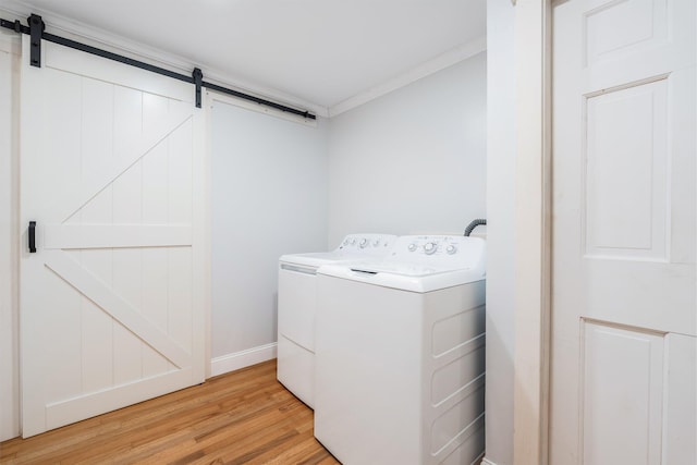 laundry area featuring washing machine and clothes dryer, laundry area, ornamental molding, light wood-style floors, and a barn door