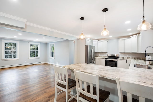 kitchen with light stone countertops, a peninsula, a sink, appliances with stainless steel finishes, and baseboard heating