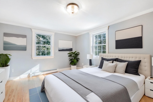 bedroom with a baseboard heating unit, baseboards, wood finished floors, and crown molding