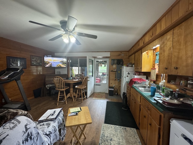 kitchen featuring ceiling fan, sink, wood walls, and dark wood-type flooring