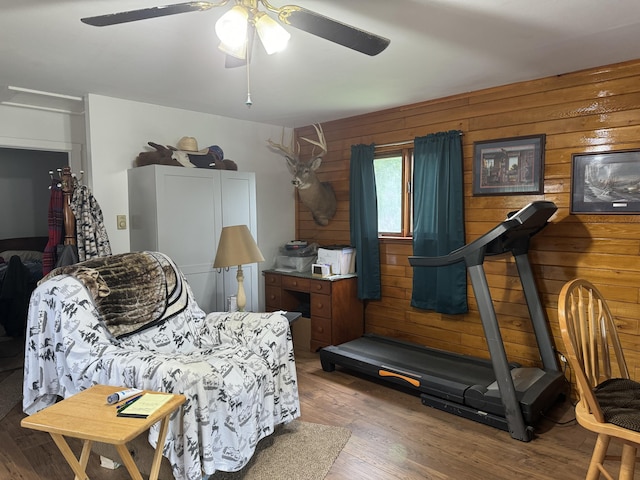 bedroom with ceiling fan, wood walls, and hardwood / wood-style flooring