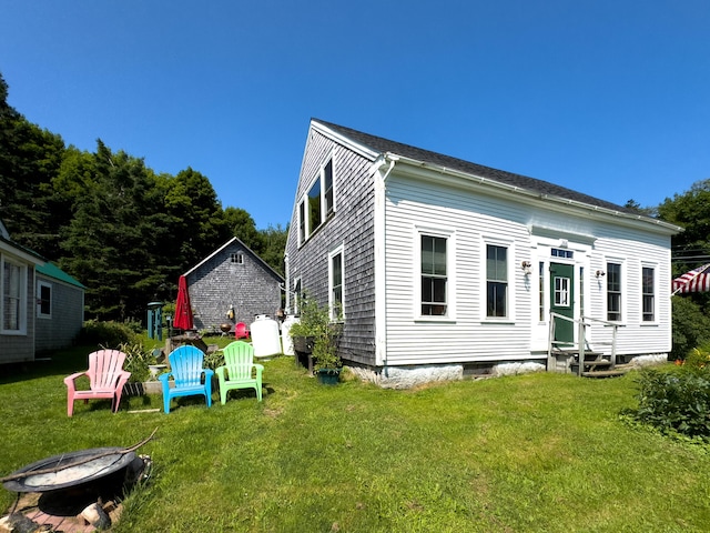 rear view of house with a yard and a fire pit