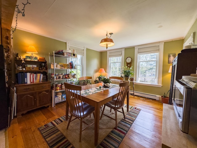 dining space with a baseboard heating unit and hardwood / wood-style floors