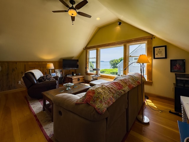 living room featuring ceiling fan, lofted ceiling, wood-type flooring, and wood walls