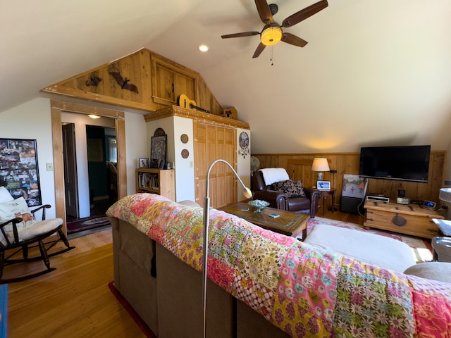 living room with ceiling fan, lofted ceiling, wooden walls, and wood-type flooring