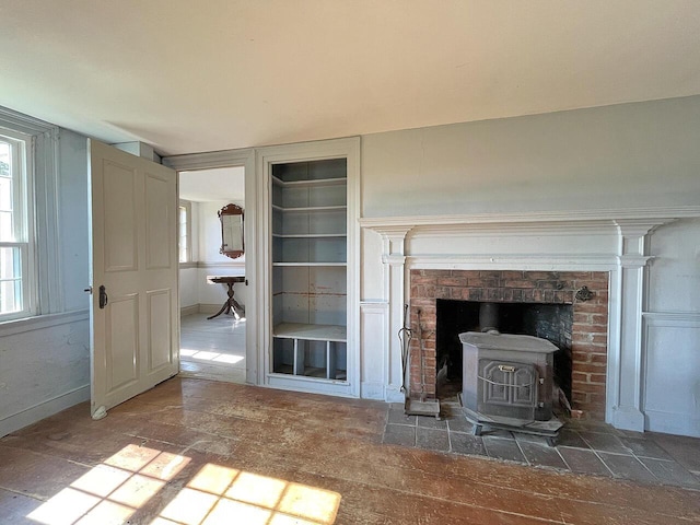 unfurnished living room featuring a wood stove and built in features