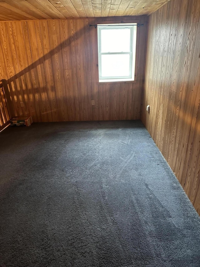 spare room featuring carpet, wood ceiling, and wood walls