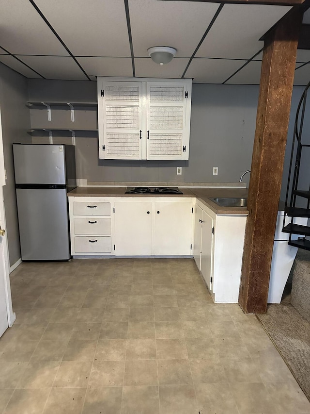 kitchen featuring white cabinetry, sink, black electric cooktop, and stainless steel refrigerator