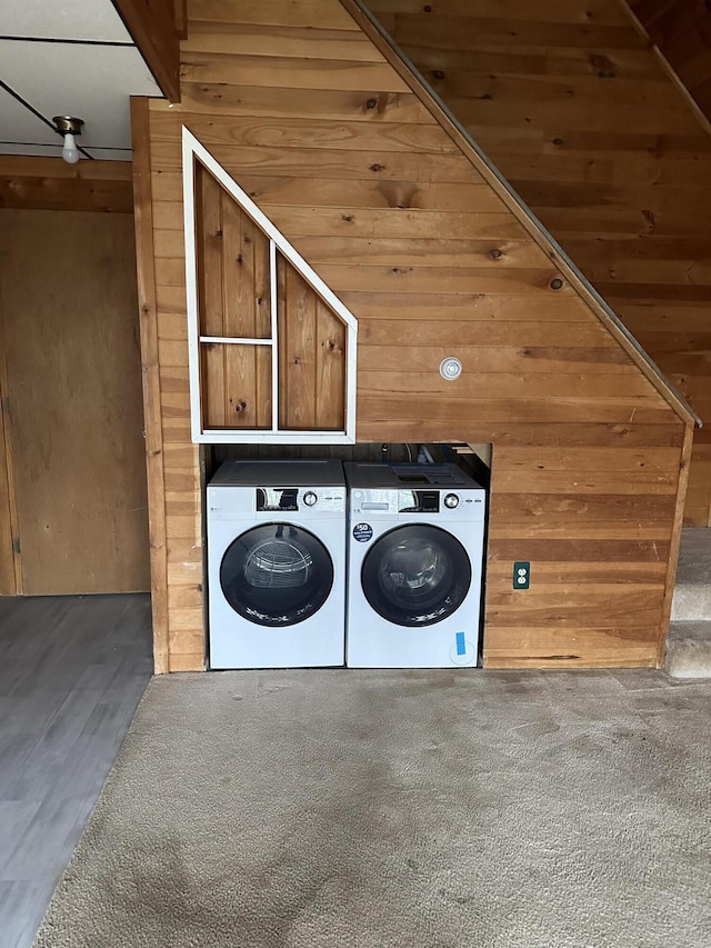 clothes washing area featuring carpet, wood walls, and washing machine and clothes dryer