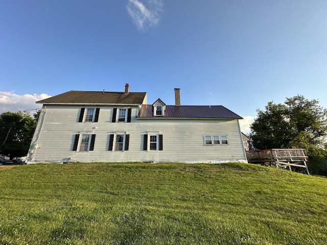 rear view of property featuring a wooden deck and a lawn