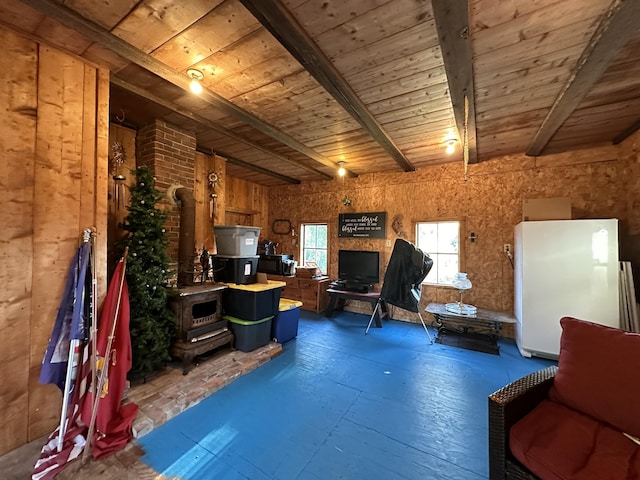 interior space with a wood stove, wooden ceiling, beam ceiling, and wood walls