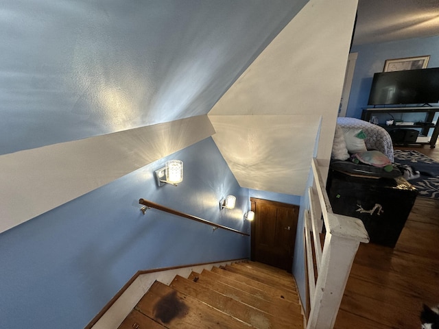 staircase with hardwood / wood-style floors and vaulted ceiling