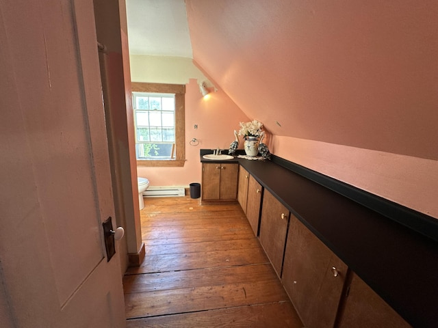 interior space with baseboard heating, sink, vaulted ceiling, and light wood-type flooring