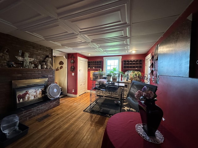 interior space featuring coffered ceiling, a brick fireplace, and hardwood / wood-style flooring