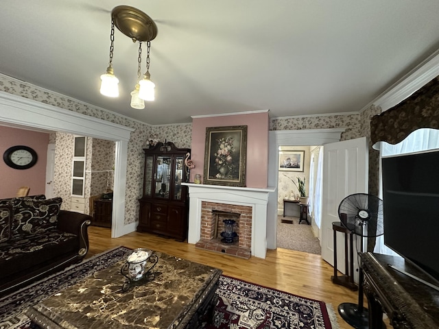 living room featuring crown molding, a brick fireplace, and light wood-type flooring