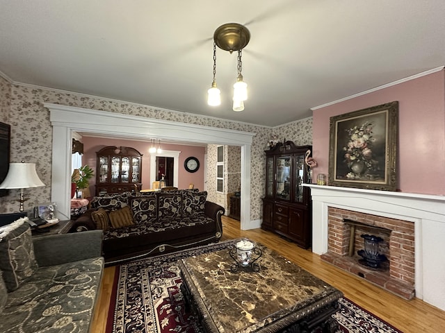 living room featuring crown molding, light hardwood / wood-style floors, and a brick fireplace