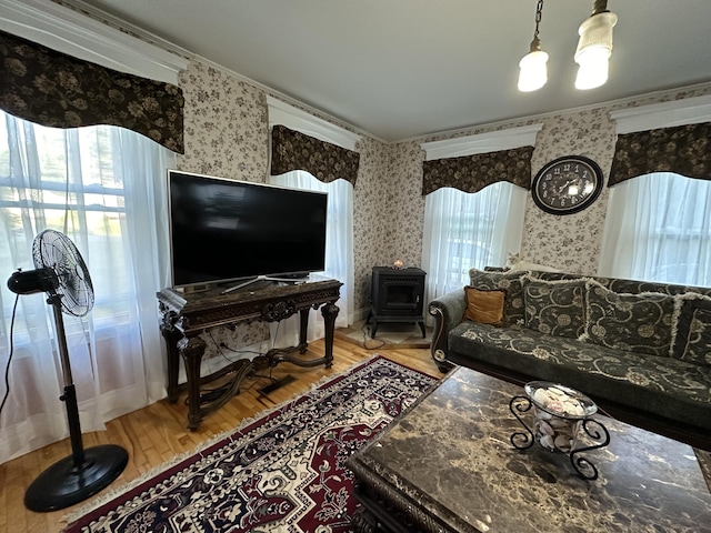 living room featuring hardwood / wood-style flooring, crown molding, and a wood stove