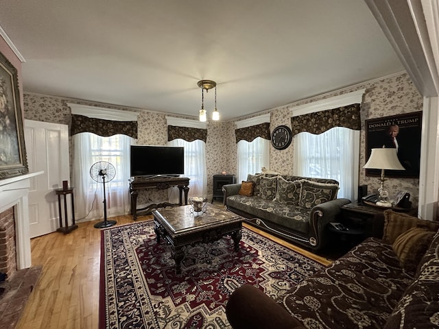 living room with ornamental molding, a brick fireplace, and light hardwood / wood-style flooring