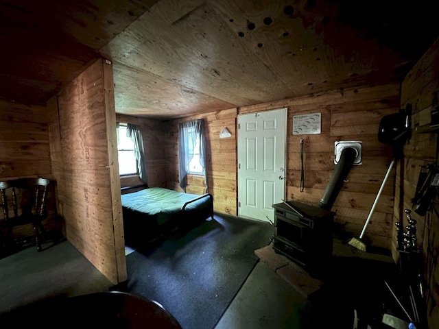 bedroom with wooden ceiling, a wood stove, and wooden walls