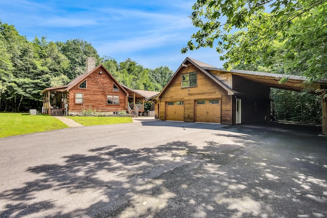 log cabin with a carport, a front yard, and a garage