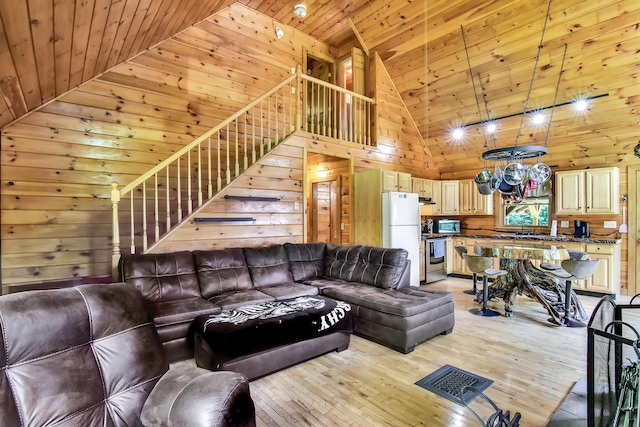 living room featuring wood walls, high vaulted ceiling, sink, light hardwood / wood-style floors, and wood ceiling