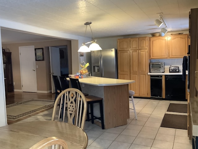 kitchen featuring dishwasher, pendant lighting, a kitchen bar, light tile patterned floors, and stainless steel fridge