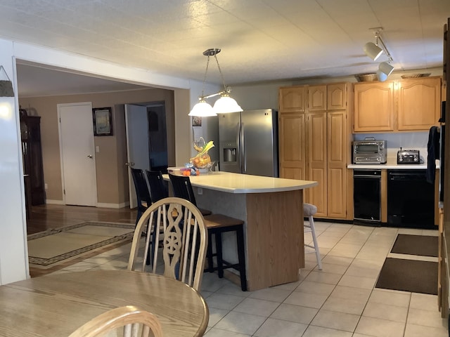 kitchen featuring dishwasher, stainless steel refrigerator with ice dispenser, a breakfast bar area, light tile patterned floors, and rail lighting