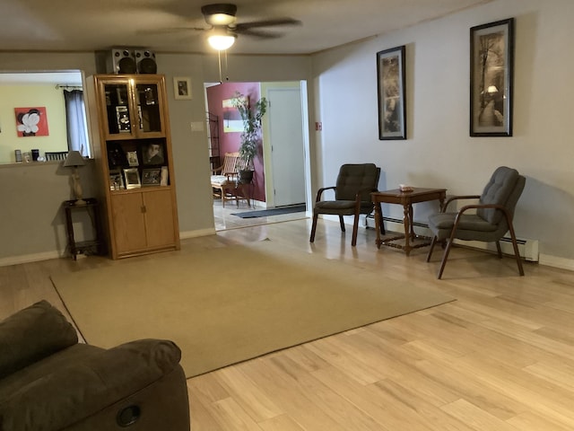 sitting room featuring ceiling fan, baseboard heating, and hardwood / wood-style floors