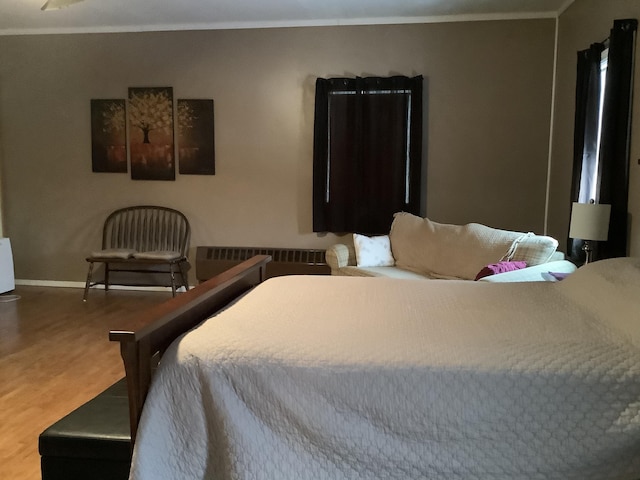 bedroom featuring radiator, ornamental molding, and wood-type flooring