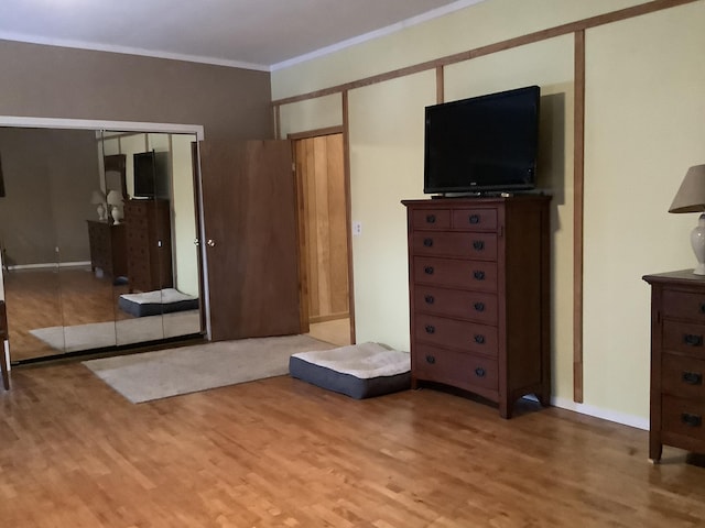 unfurnished bedroom featuring a closet, ornamental molding, and light wood-type flooring