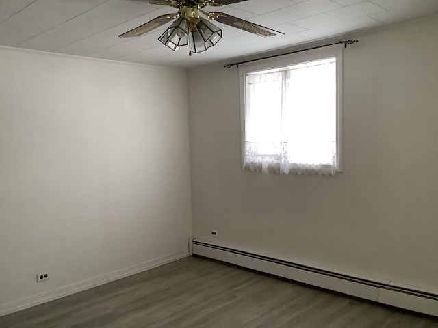 empty room with ceiling fan, baseboard heating, wood-type flooring, and crown molding