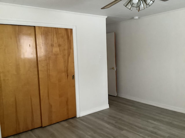 unfurnished bedroom with ceiling fan, crown molding, a closet, and dark hardwood / wood-style flooring