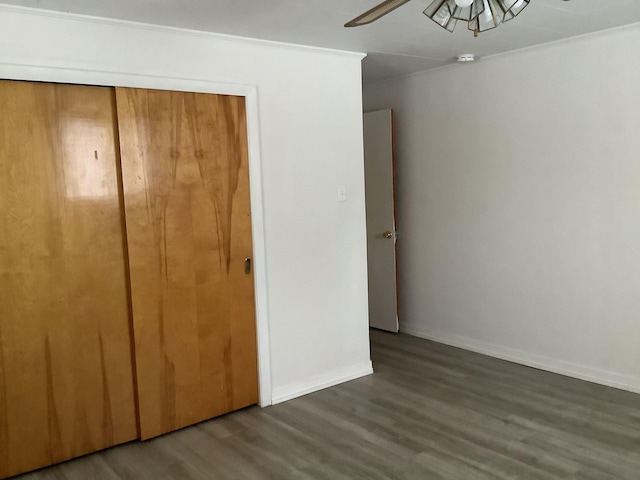 unfurnished bedroom featuring a closet, ornamental molding, dark hardwood / wood-style floors, and ceiling fan