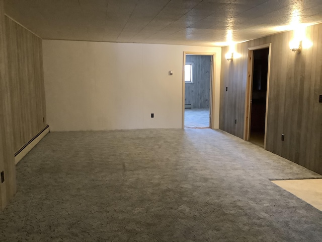 carpeted empty room featuring a baseboard heating unit and wooden walls