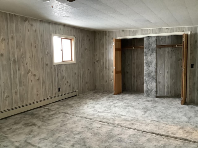 unfurnished bedroom with baseboard heating and wood walls