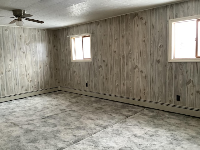 unfurnished room with ceiling fan, wooden walls, and a baseboard radiator